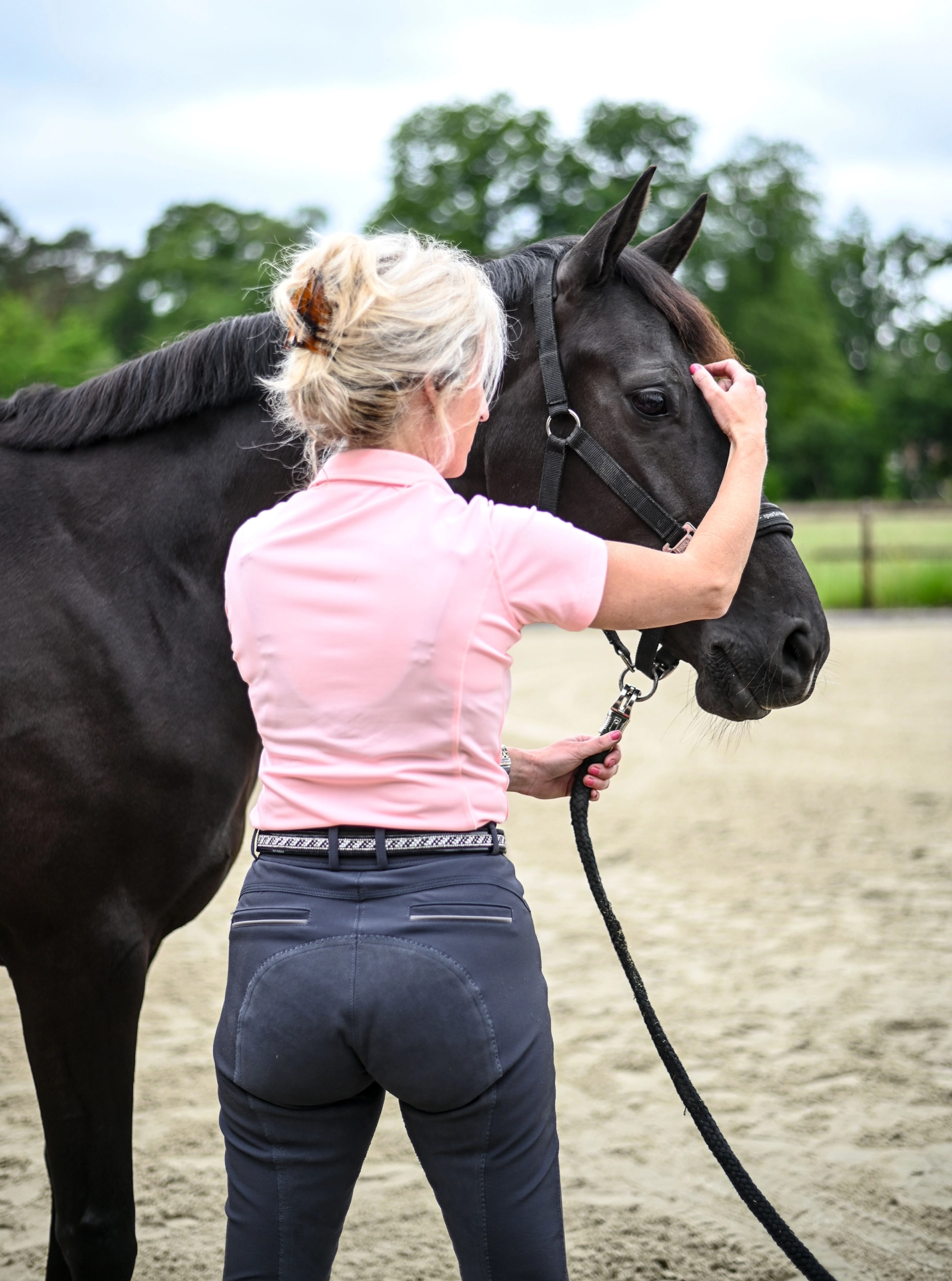 Sabrina Barmentloo van 'Osteopaat voor je Paard' inspecteert het hoofd van een zwart paard tijdens een consult. Deze afbeelding illustreert een pagina over voedingsadvies voor paarden, gericht op het bevorderen van een gezond en gelukkig paard door middel van optimale voeding.